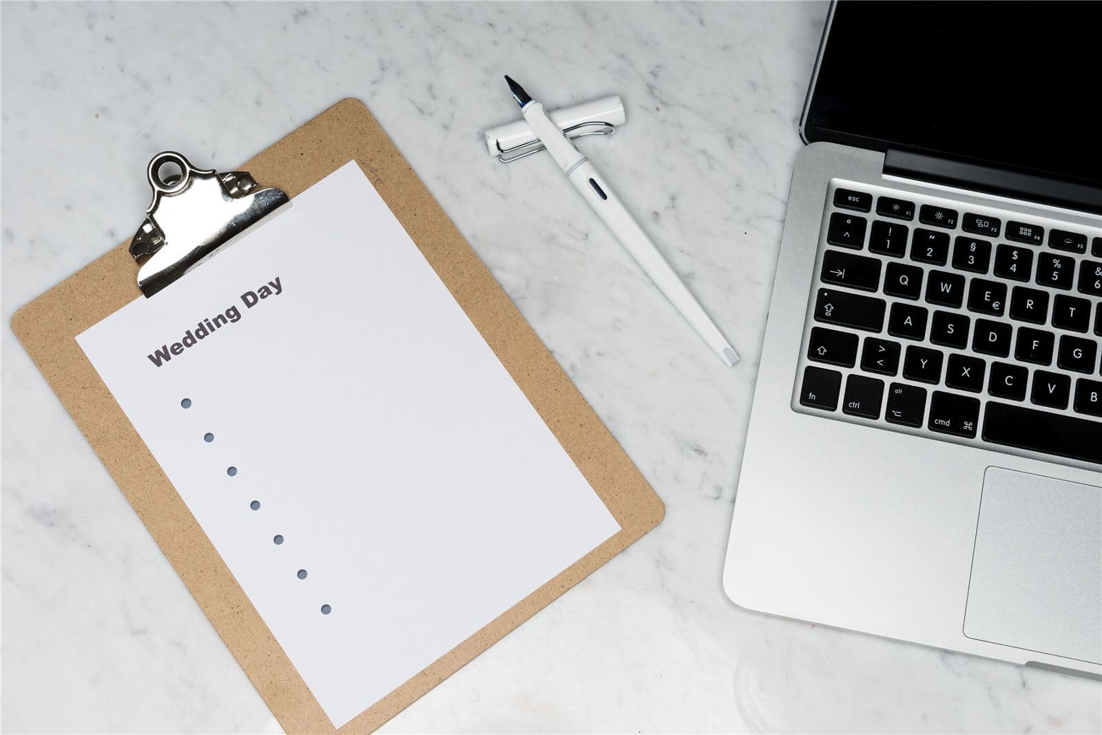 Wedding day planning checklist on a clipboard next to a laptop