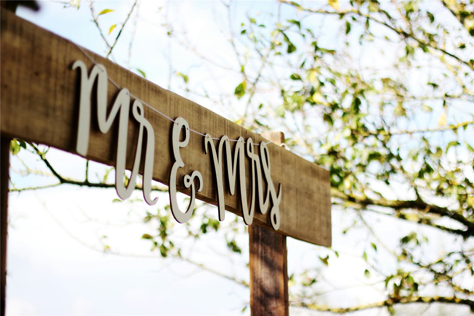 Mr and Mrs sign hanging on a wooden arch at a wedding